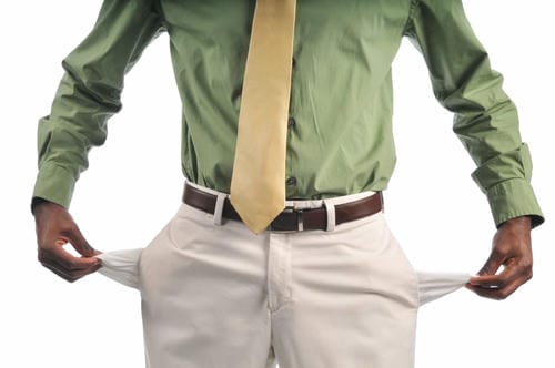 A man pulls out the empty pockets of his pants, visually representing being completely out of money after paying rent and other bills.