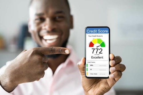A man pointing to his smartphone showing an excellent credit score of 772.
