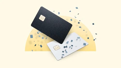 A black and a white credit card with confetti-like fragments around them.