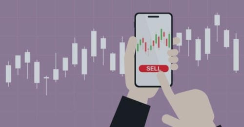 A hand pressing the "SELL" button on a smartphone, with candlestick charts in the background.