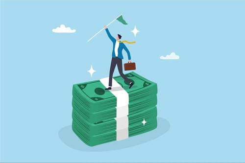 An illustration of a businessman standing triumphantly on a stack of cash, holding a briefcase and a flag.